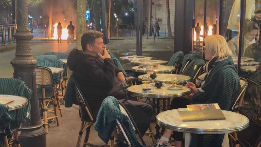 Krawalle am Triumphbogen: Pärchen genießt Drinks vor Flammen